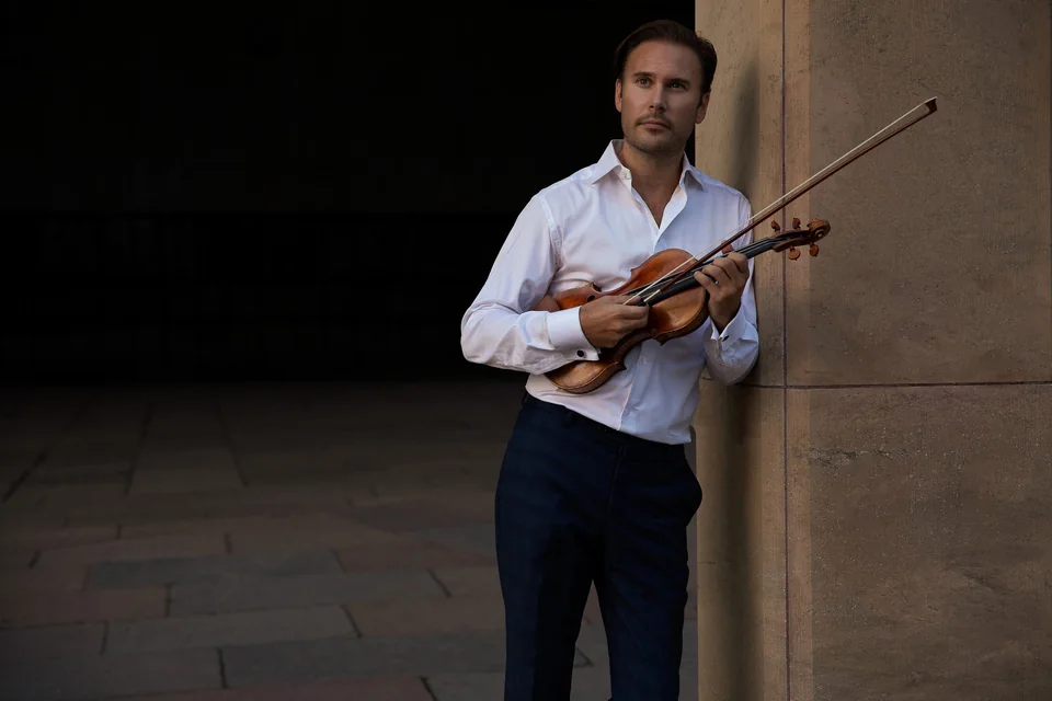Christian Svarfvar med violin och stråke i vit skjorta