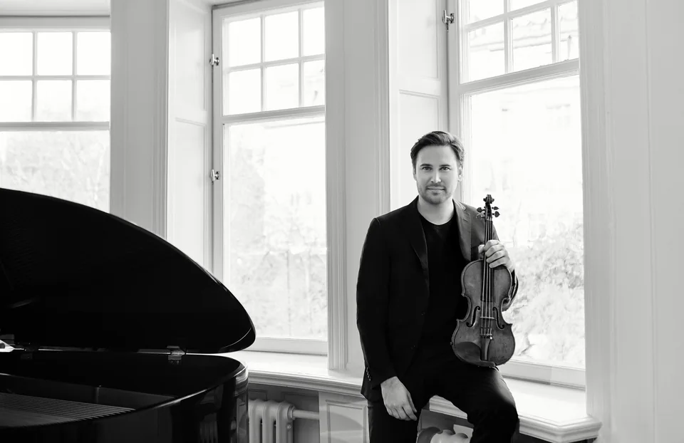 Christian Svarfvar with violin beside a grand piano