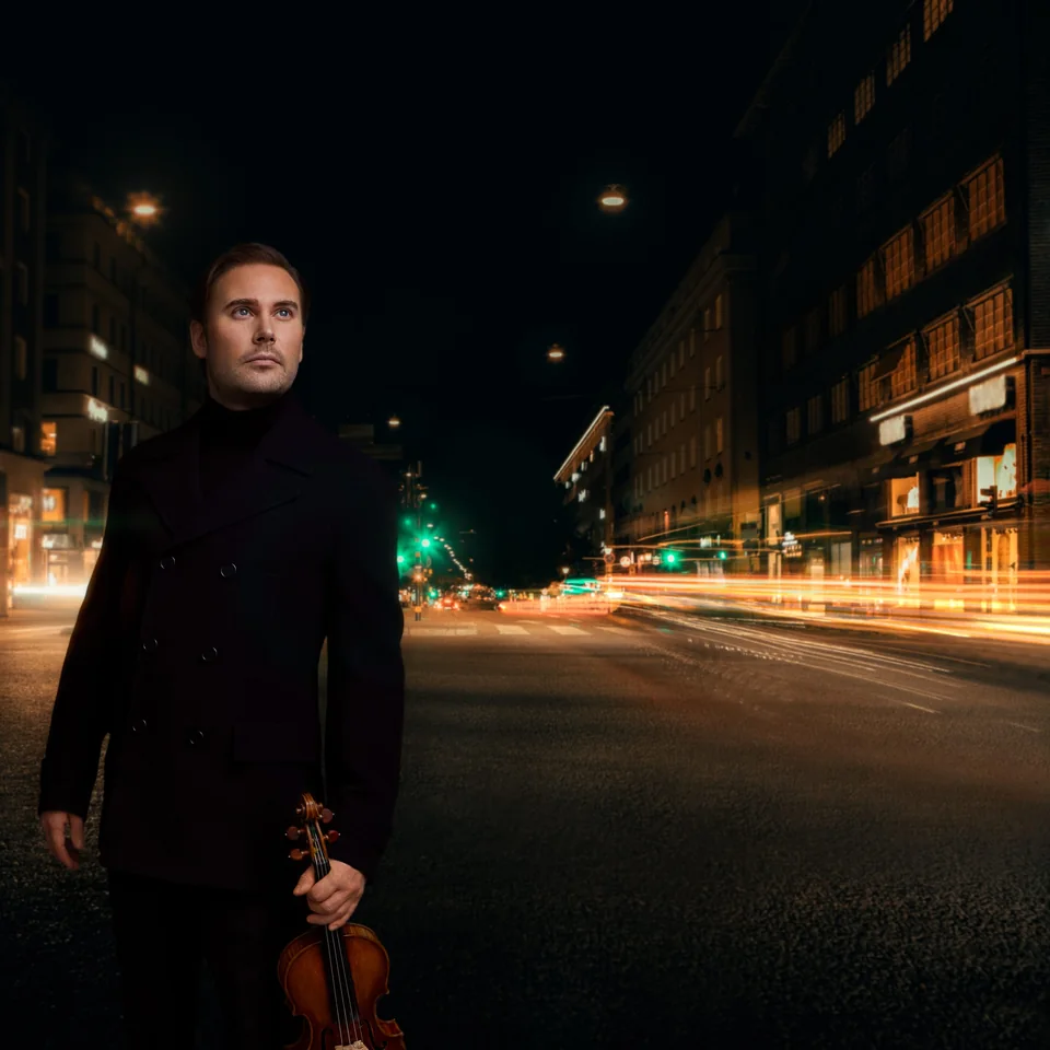 Christian Svarfvar med violin på en stadsgata på kvällen